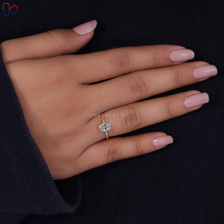 Diamondsbyuk ring showcasing an oval shaped engagement ring with a yellow gold band.
