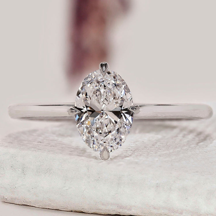 Oval solitaire engagement ring with white gold band.
