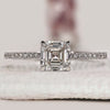 Asscher cut diamond ring with round pave accents.