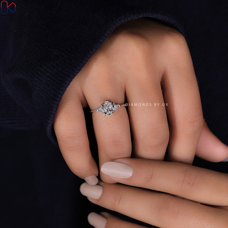 Round side stone ring with a tear drop diamond for a modern and elegant design.