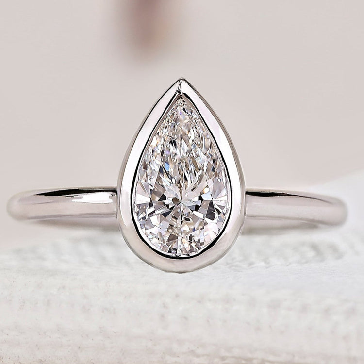 Pear cut diamond engagement ring with bezel setting.
