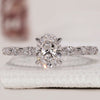 Oval diamond engagement ring crafted with marquise and round side stones in white gold.