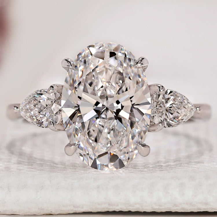 Three stone diamond ring with oval centre diamond.
