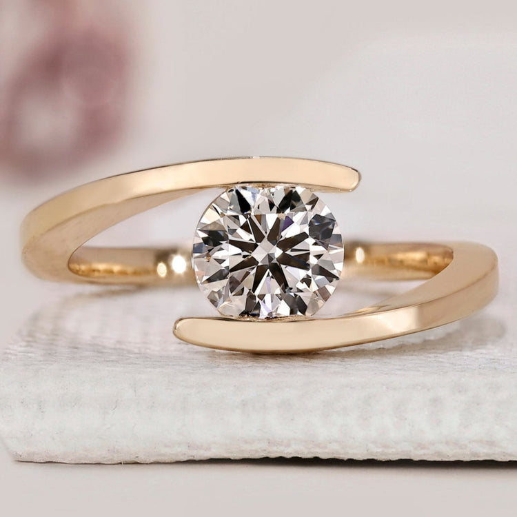Round diamond ring crafted in yellow gold with a unique bypass setting.