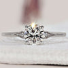 Side stone engagement ring featuring elegant round cut diamonds.
