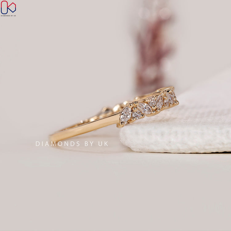 Yellow gold wedding band featuring marquise and round stones.
