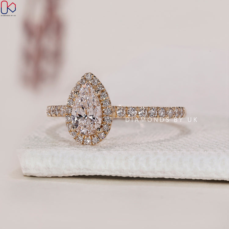 Yellow gold ring with a pear shaped centre and a delicate pave diamond ring band.
