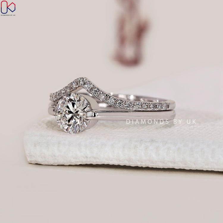 Curved wedding band paired with solitaire engagement ring and round diamond.
