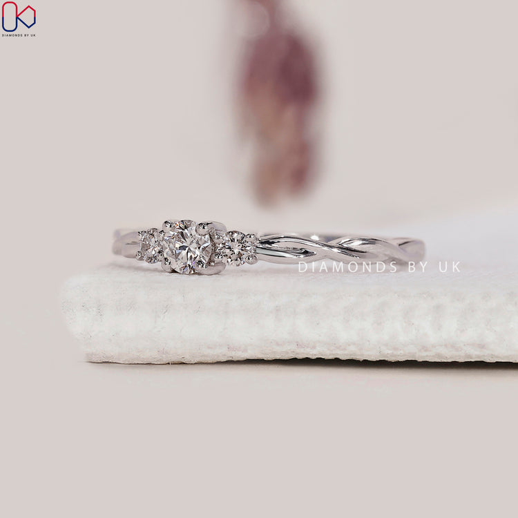 Minimalist engagement ring with three round diamonds.
