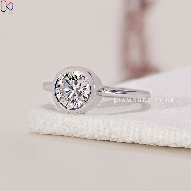 Diamondsbyuk ring featuring a bezel set diamond ring with a round diamond engagement ring.