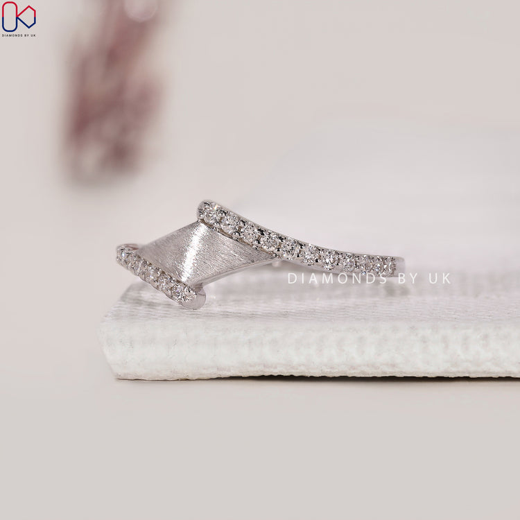 White gold band with a bypass shape and prong set round diamonds.

