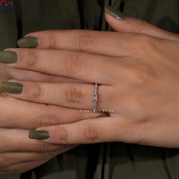 Baguette centre diamond surrounded by round diamonds in a half eternity band.
