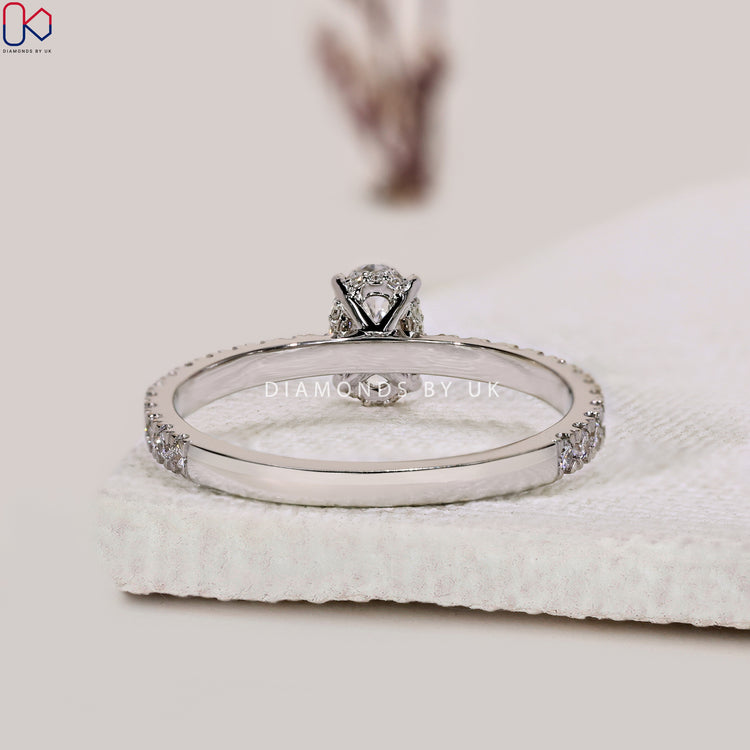 Prong setting oval engagement ring with pave details.