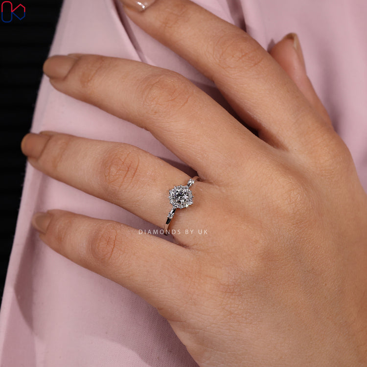 White gold engagement ring with round diamond and side stones.
