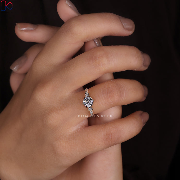 Round diamond engagement ring with a side bezel milgrain set.
