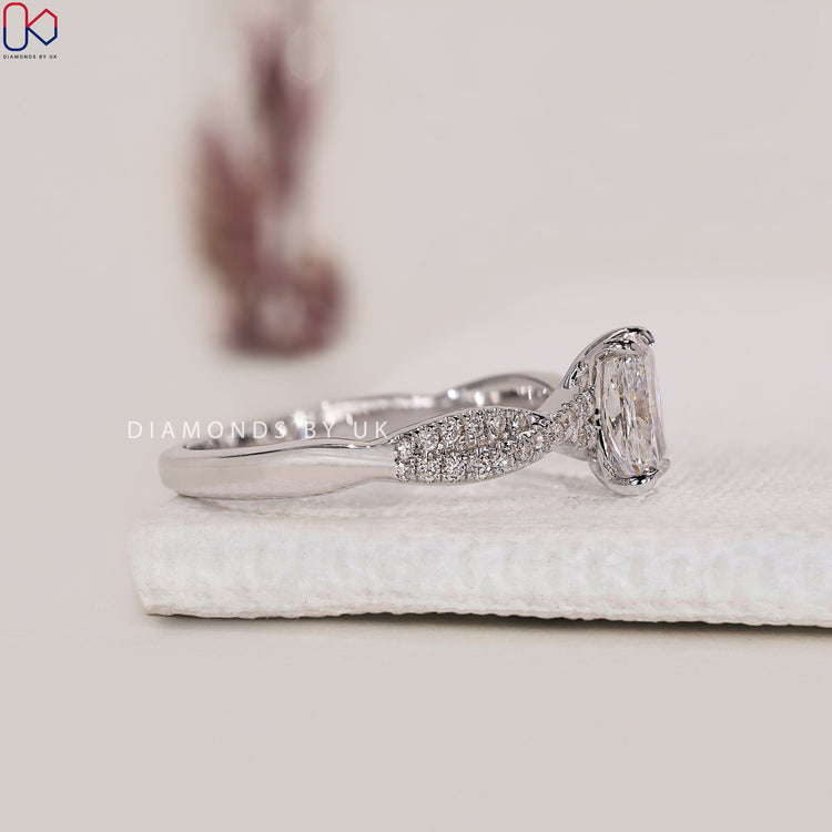 White Gold Ring with a cushion cut diamond and round side diamonds, set in a 4 prong claw setting for an elegant look.
