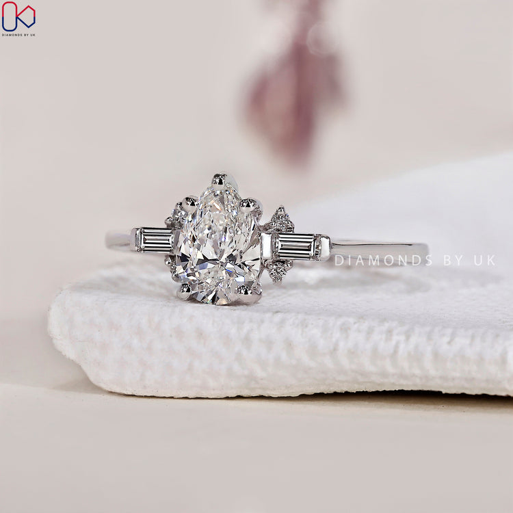 Tear drop diamond ring with baguette side stones for a unique and timeless look.