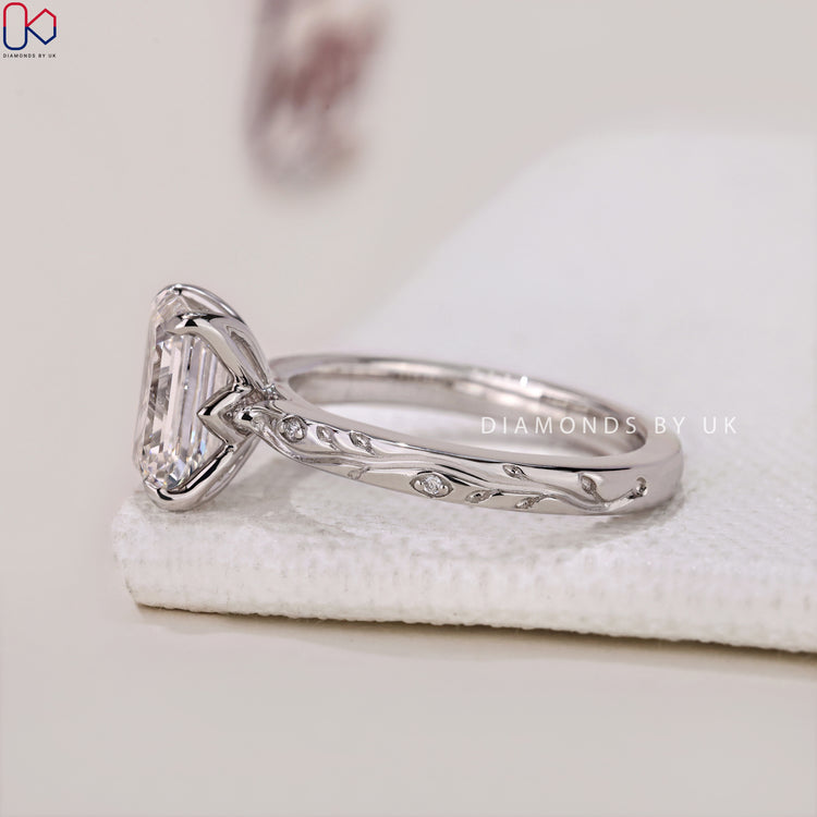 4 Prong Claw Setting Ring with Emerald Cut Diamond and side diamonds, showcasing unique artistry.
