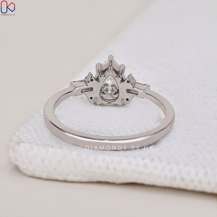 Shop to buy engagement ring featuring a tear drop diamond design with side stones.