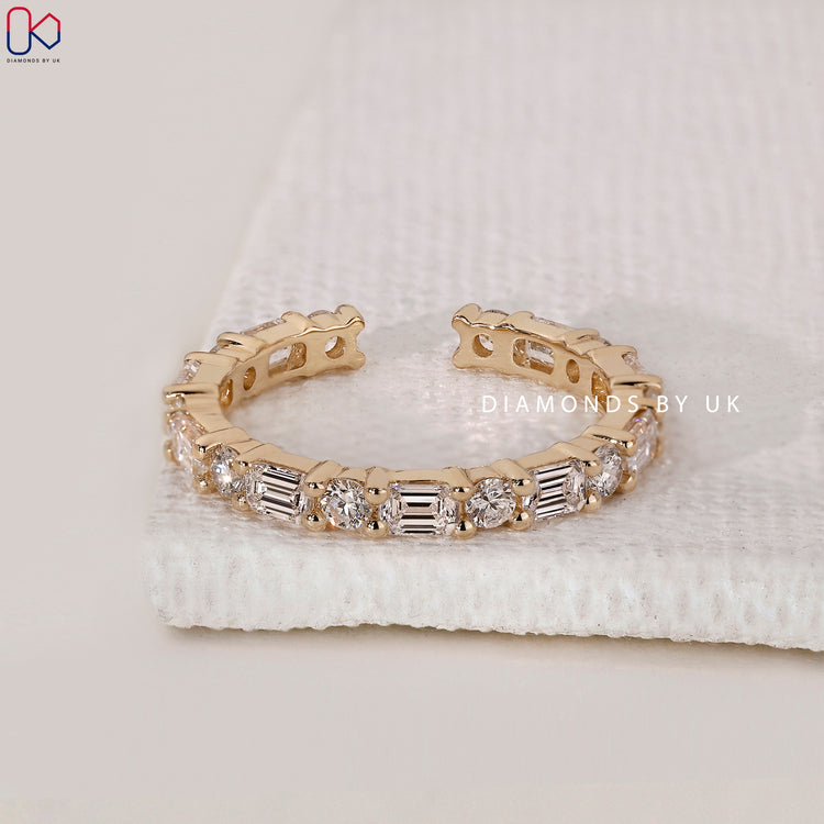 Yellow gold wedding band with emerald and round stones.
