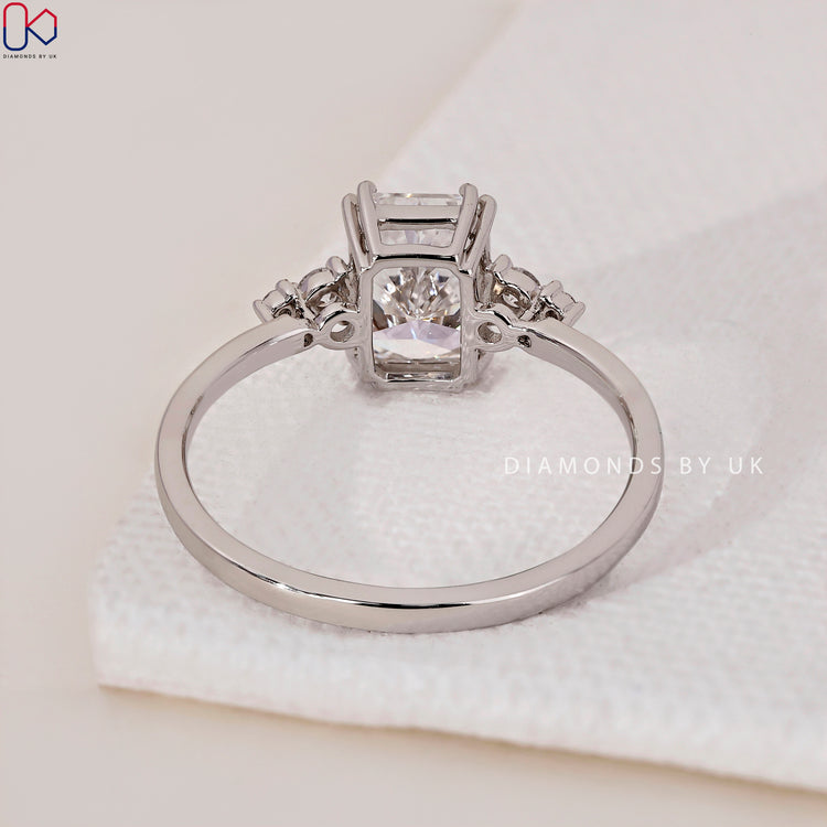Handmade jewellery with a radiant cut diamond and round side stone engagement ring.