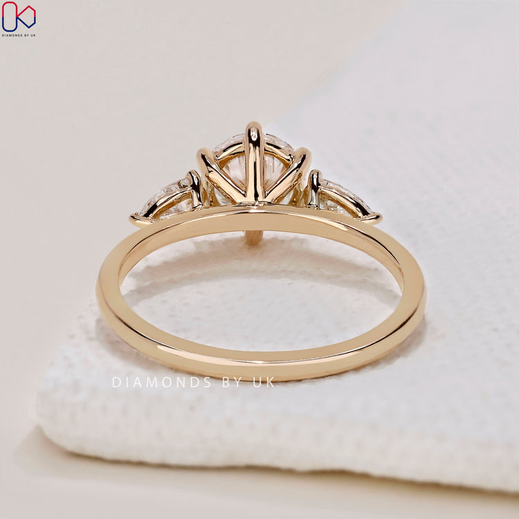 Shop to buy engagement ring featuring a round diamond ring with pear side stones.
