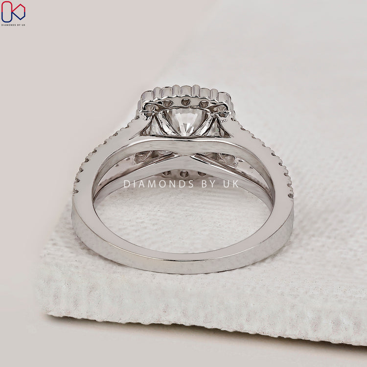 Engagement ring with round diamond, split shank, and halo.