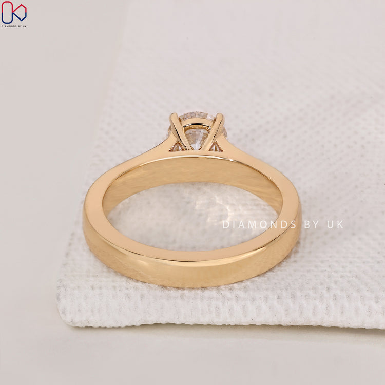Buy Engagement Ring with a round diamond solitaire design, prong setting, and wide band crafted in yellow gold.
