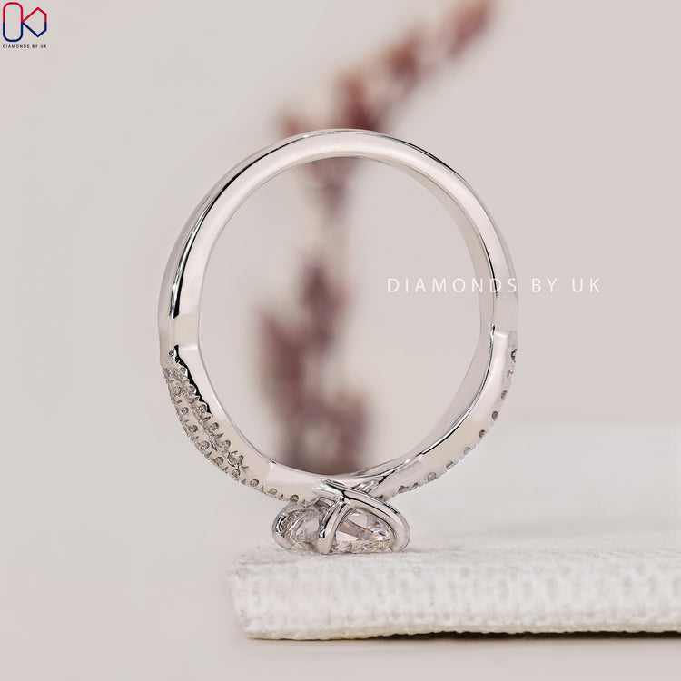 Handmade Ring with a cushion cut diamond and round side diamonds, set in a twisted band, made in white gold.

