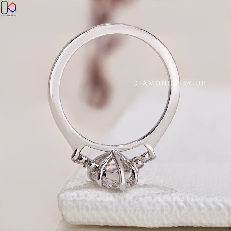 Diamondsbyuk engagement ring with round side stones.
