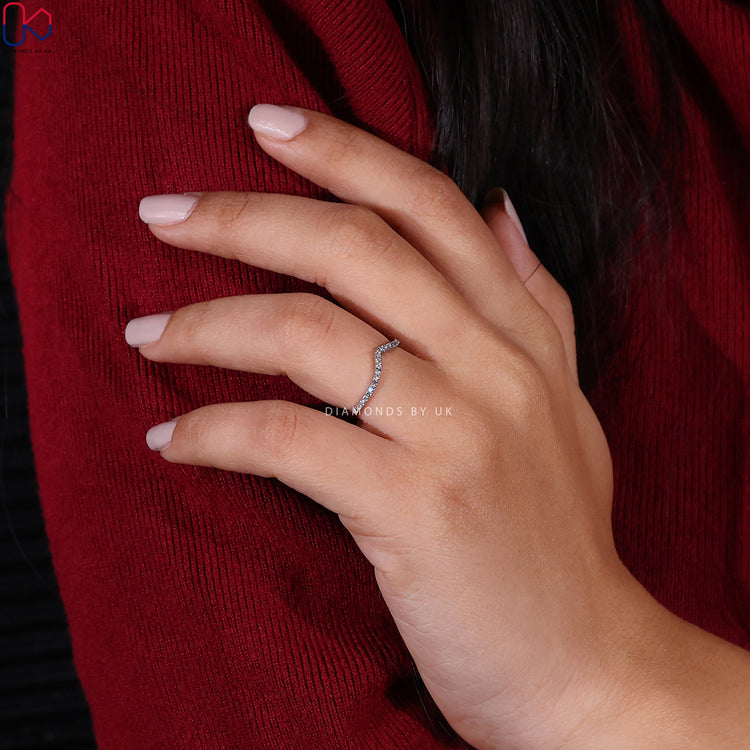 Prong set wedding band holding round lab grown diamonds in a flowing chevron line.
