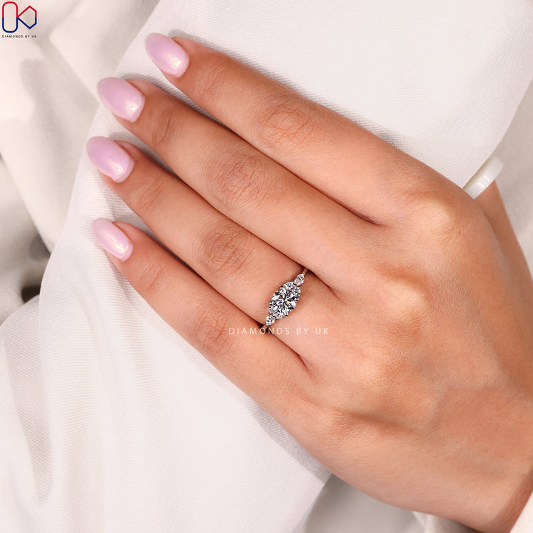 Round cut ring with prong set side diamonds.