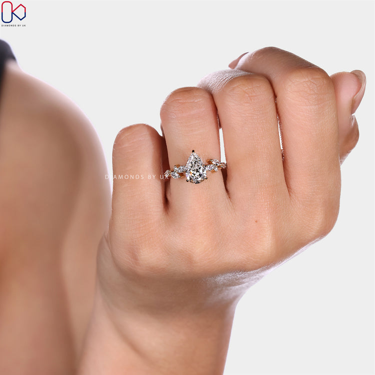 Pear diamond ring with marquise and round side stones.
