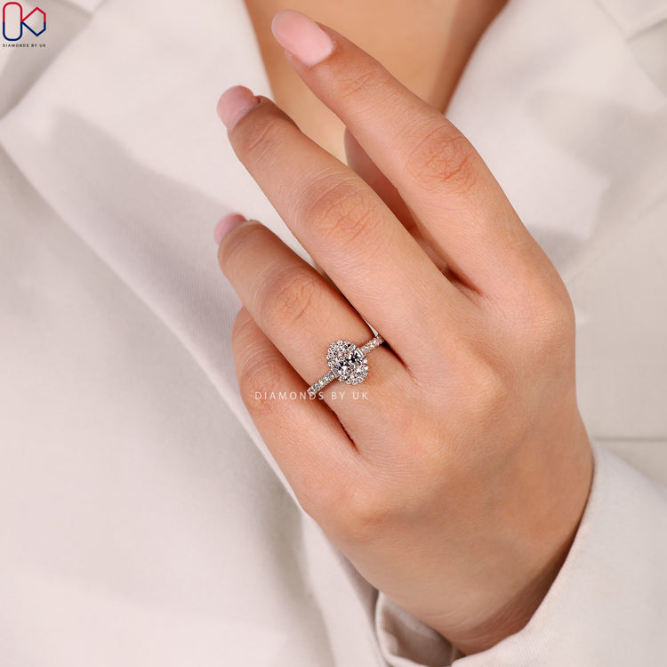 Oval ring with halo pavé and bridge accents.