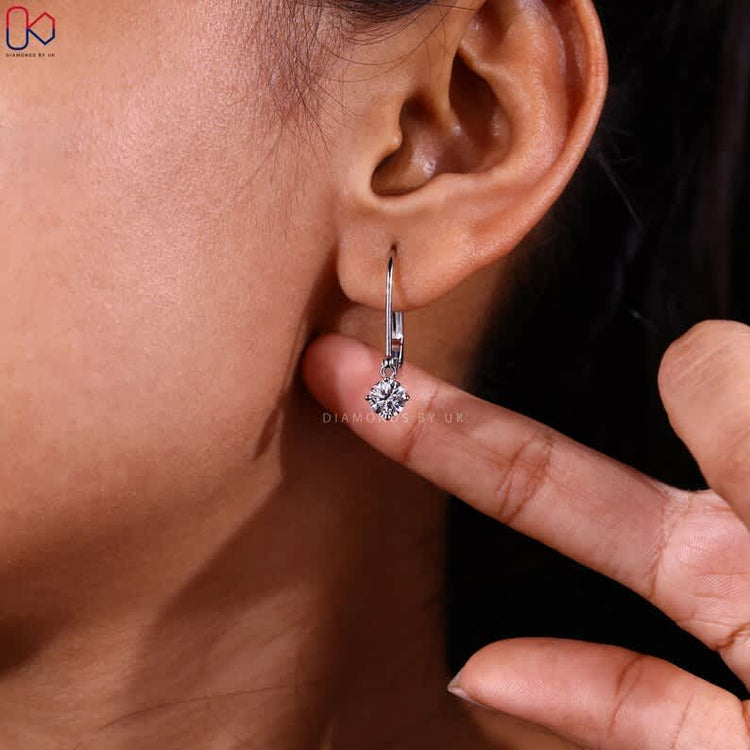 Dangle round diamond earrings with compass prongs.