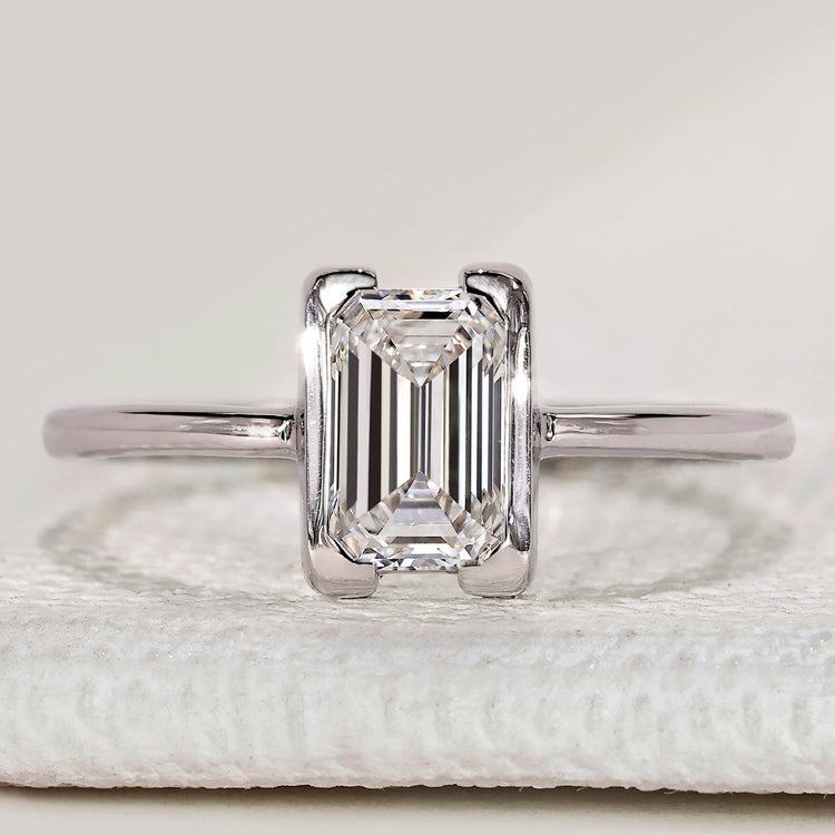 Emerald cut solitaire ring with half bezel setting.
