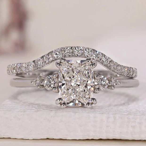 Radiant cut engagement ring with round side stones and wedding band.