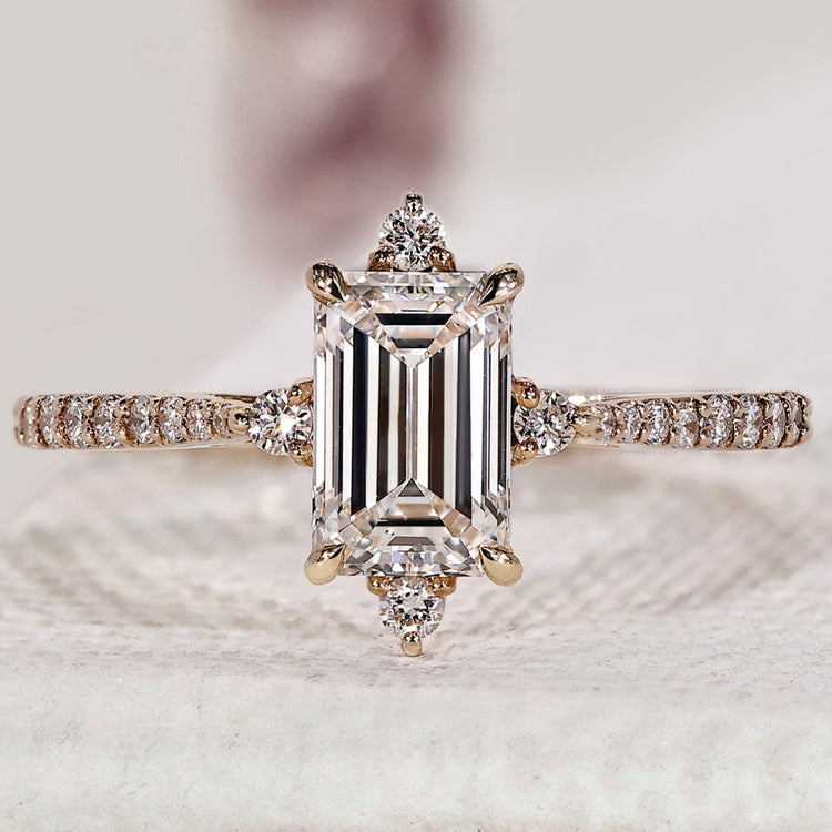 Emerald diamond engagement ring with round cut side stone.
