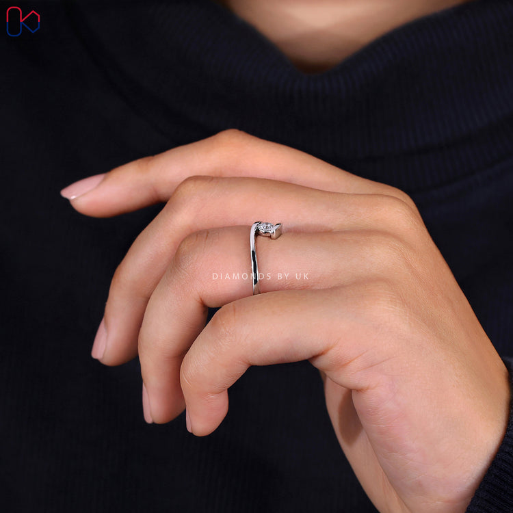 Simple ring featuring a round cut diamond ring set in a minimalist design.
