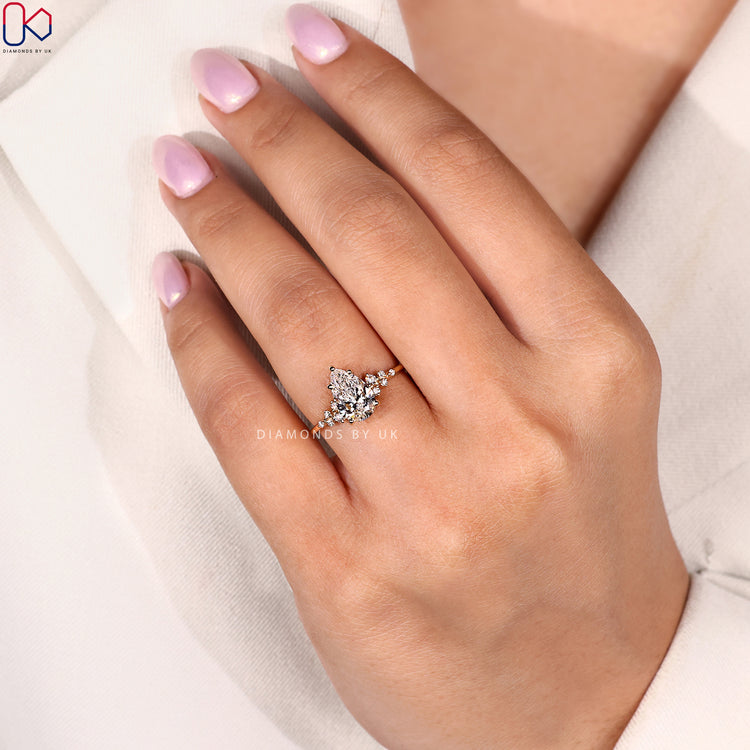 Round cut side stone engagement ring with pear centre.
