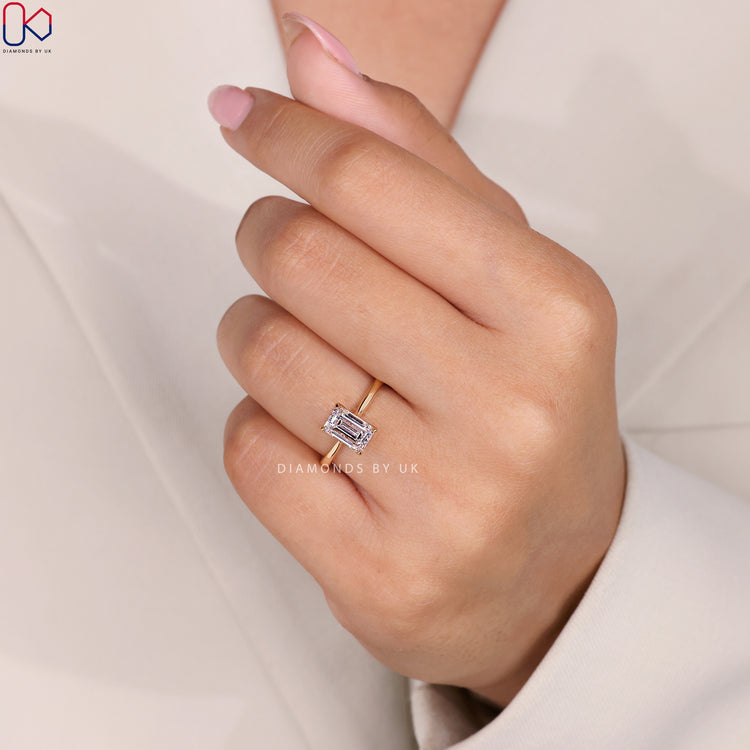 Tapered shank ring featuring an emerald cut diamond.
