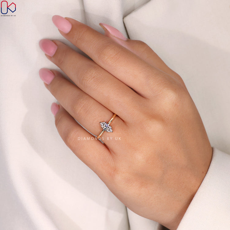 Diamondsbyuk marquise diamond engagement ring with a yellow gold setting.
