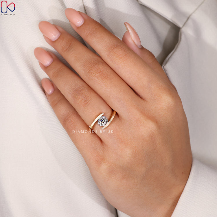 Solitaire ring with a round diamond and an open bypass form for a unique shape.