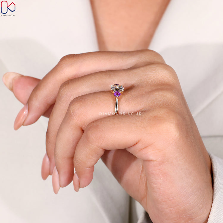 Purple round side stone diamond engagement ring.
