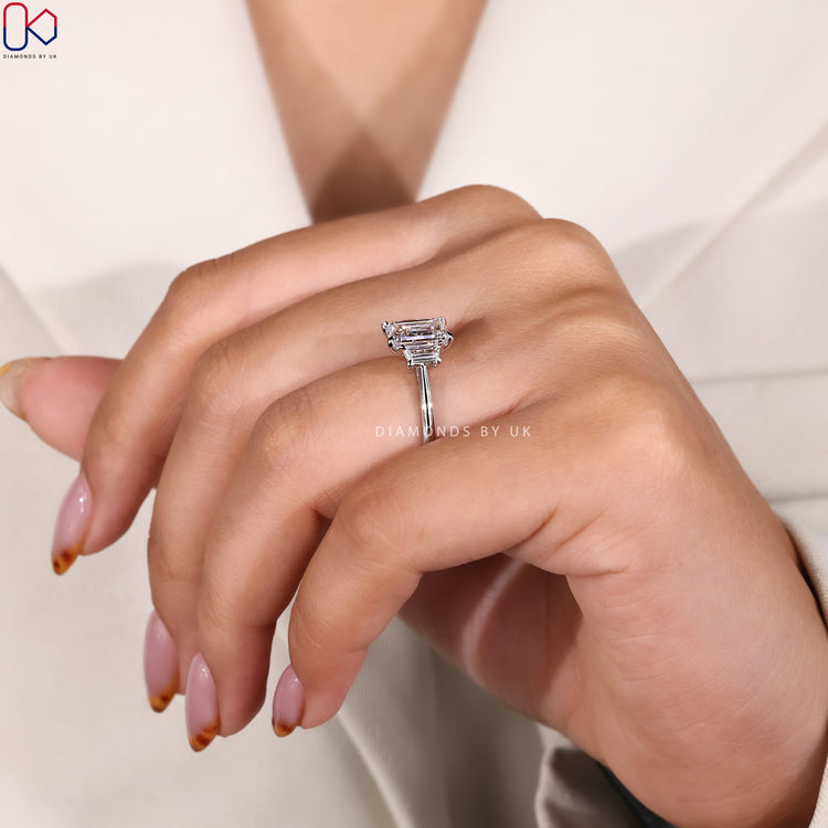 Trapezoid baguette side stones set beside emerald cut diamond.
