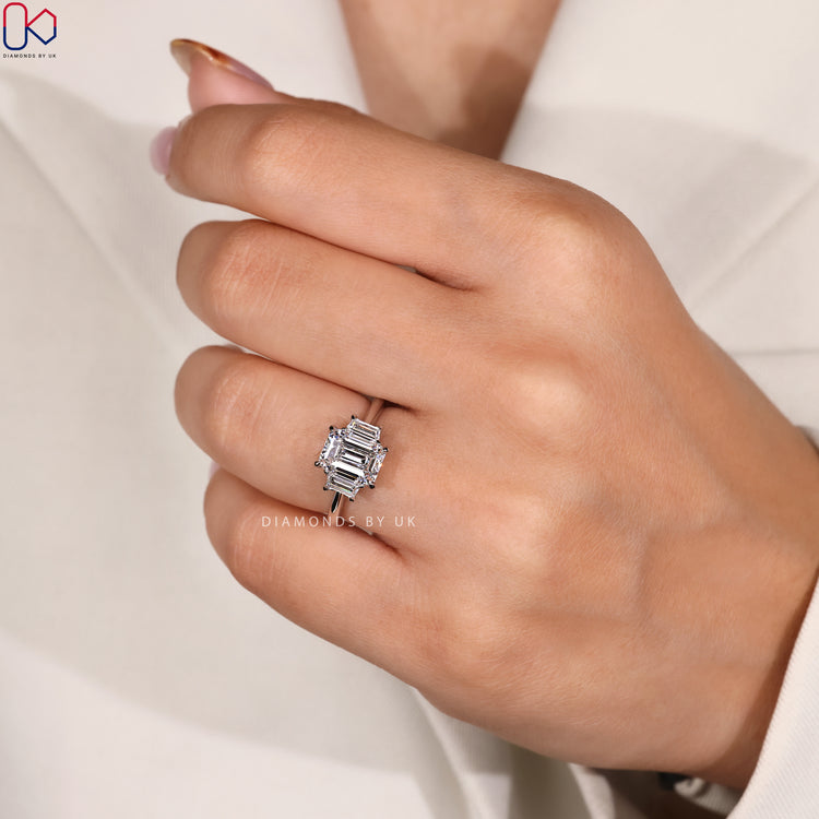 White gold diamond ring with emerald and trapezoid stones.
