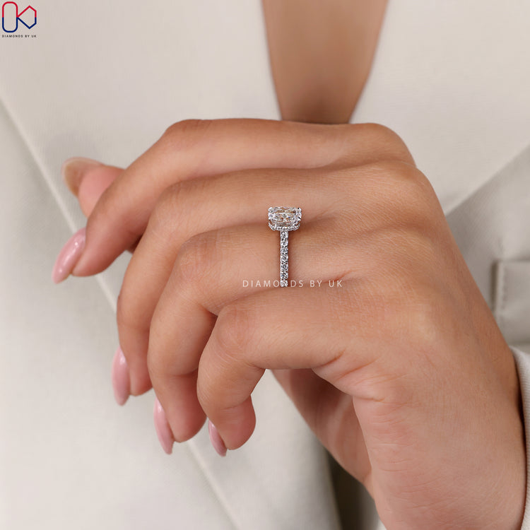 4 Prong Claw Setting Engagement Ring featuring a cushion brilliant cut diamond and round side stones in white gold.
