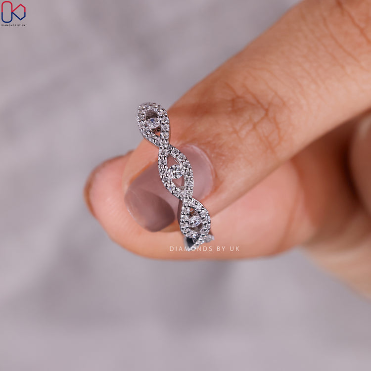 Round diamond wedding band with twisted infinity style.

