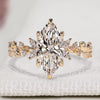 Marquise cut diamond ring with round side stone cluster.
