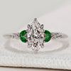 Marquise ring with dark green emerald side stones.
